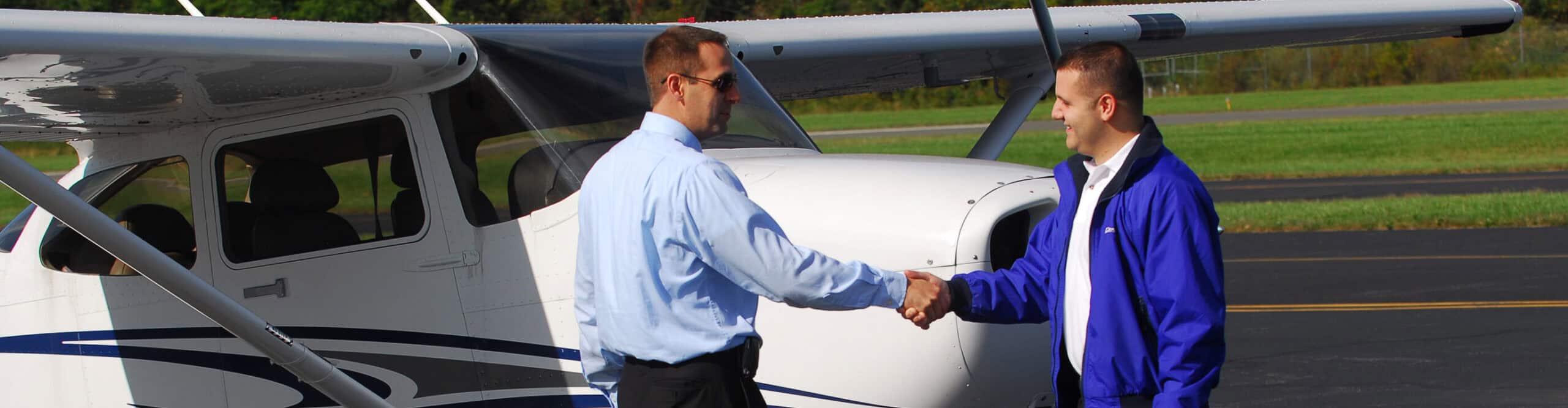 Flight instructor at Century Air Flight School shaking hands with student pilot in front of the aircraft